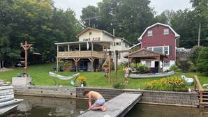 Ein Steg führt ins Wasser, im Hintergrund sind ein Haus und ein rotes Gebäude zu sehen.