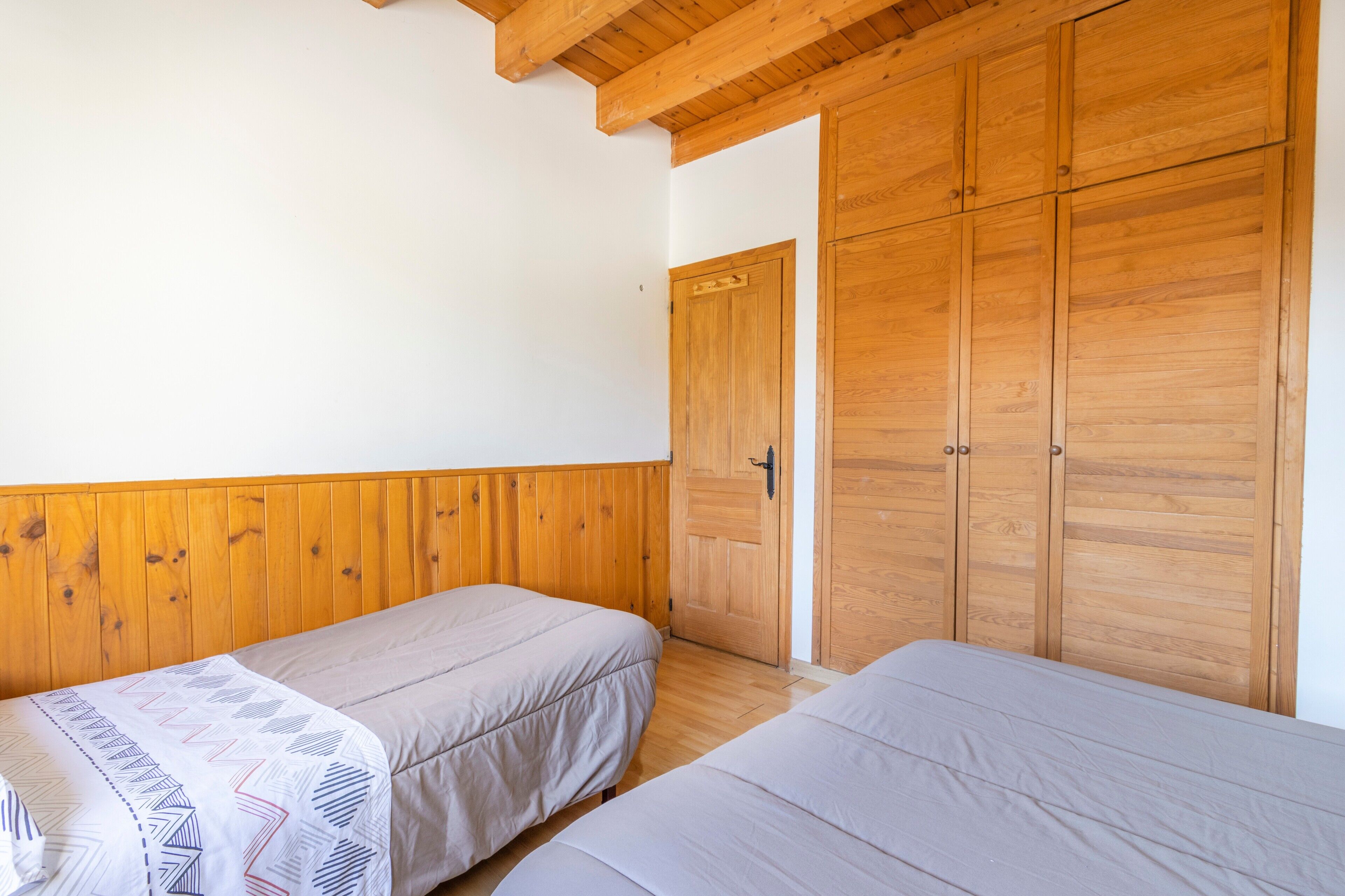 Ein Zimmer mit zwei Betten, einem Holzschrank und einer Tür.