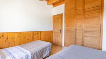 Ein Zimmer mit zwei Betten, einem Holzschrank und einer Tür.