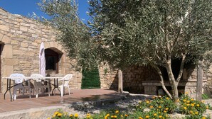 A stone building with a patio, outdoor seating, and a tree.