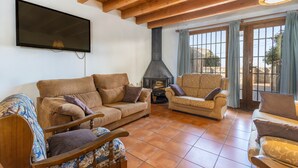 A living room with a fireplace, two sofas, a television, and a large window.