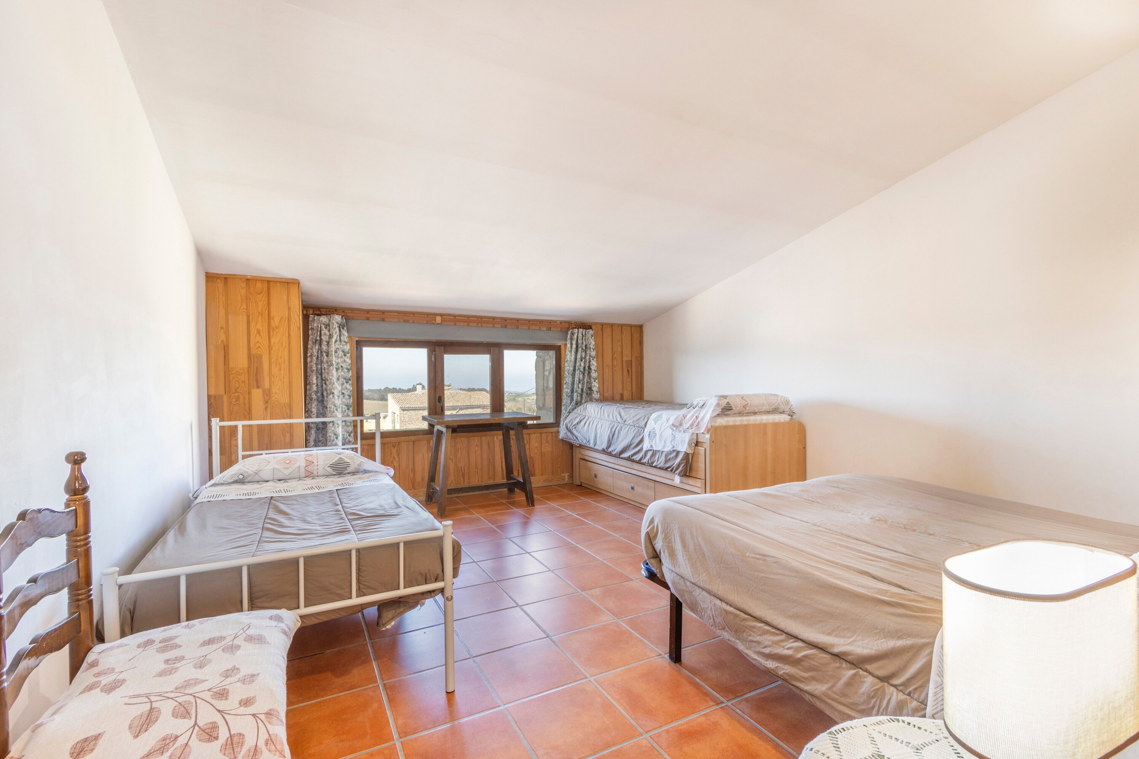A dormitory room with two beds, a window, and a view of the outside.