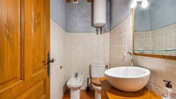A bathroom with a wooden door, a white sink, a bidet, and a toilet.