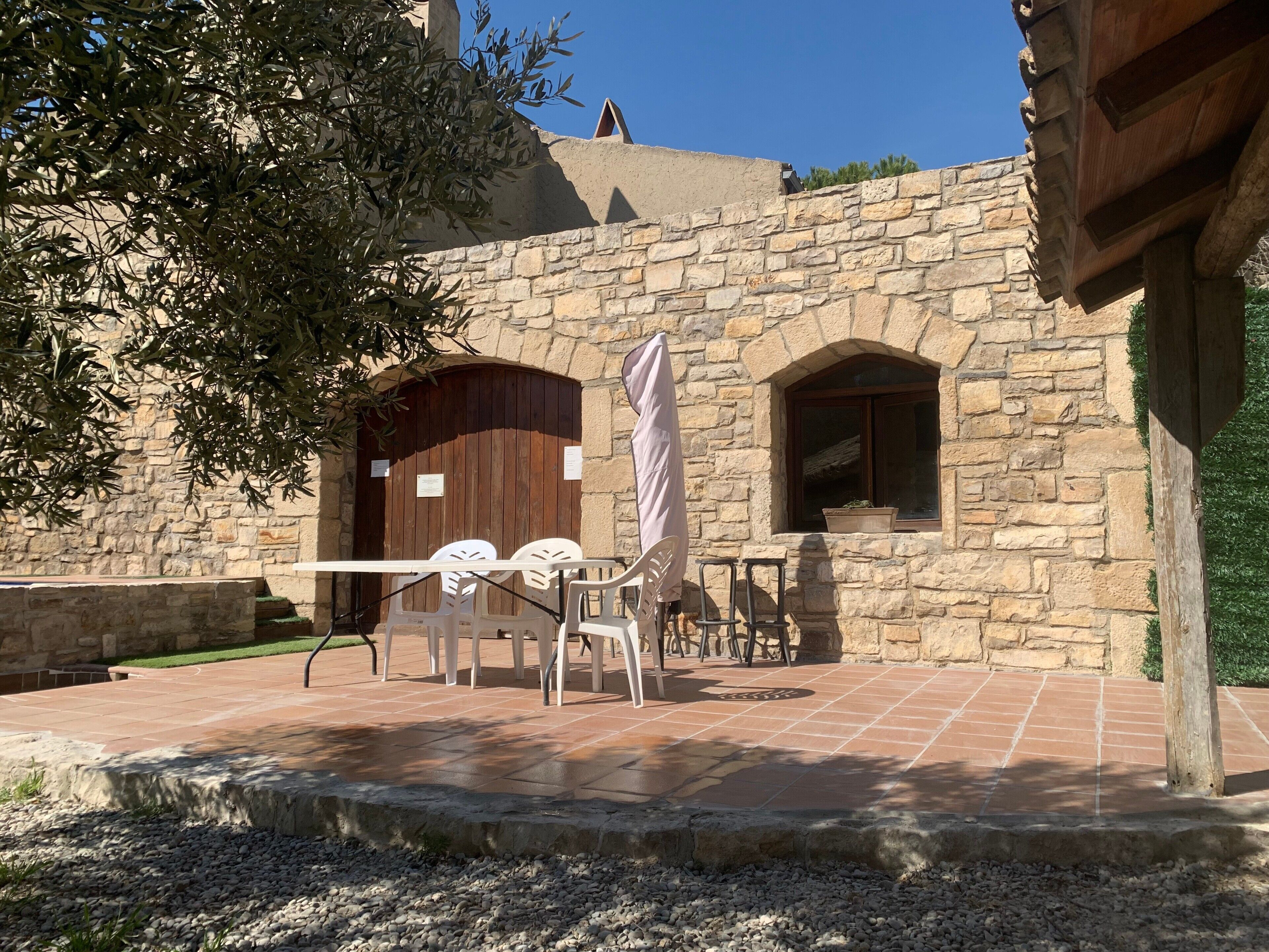 A stone building with a patio area featuring outdoor seating and a wooden door.