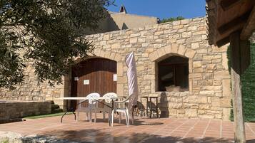 A stone building with a patio area featuring outdoor seating and a wooden door.