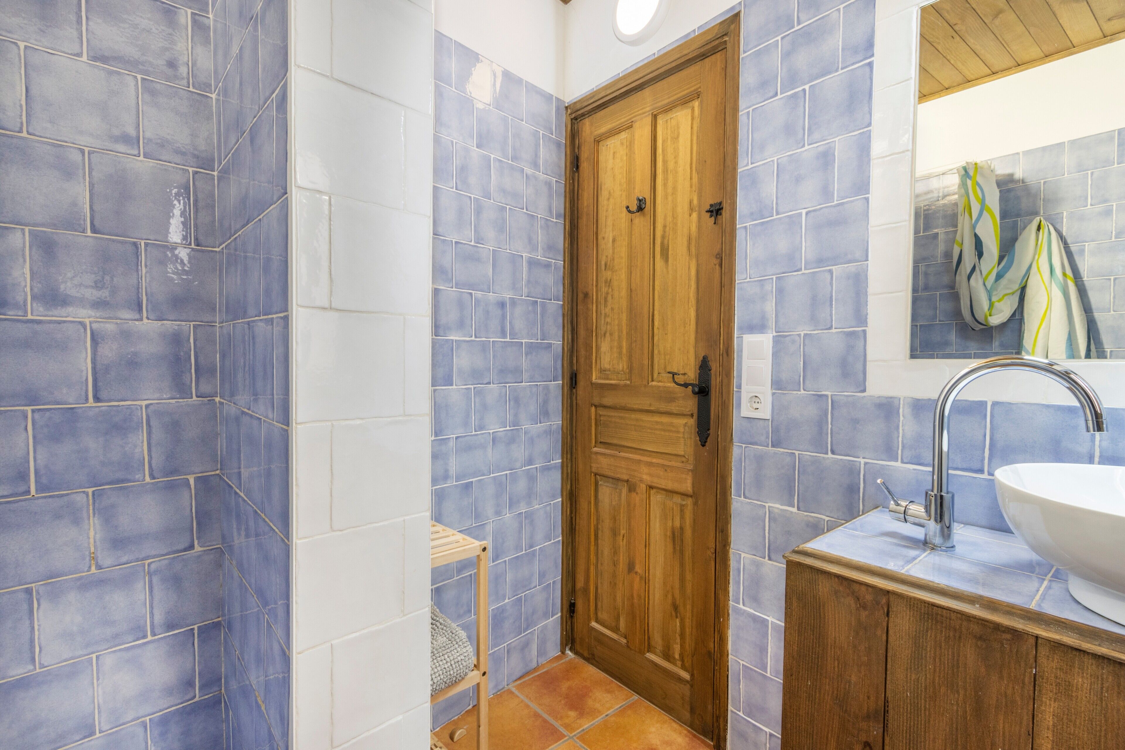 A bathroom with blue and white tiles, a wooden door, a sink, and a towel rack.