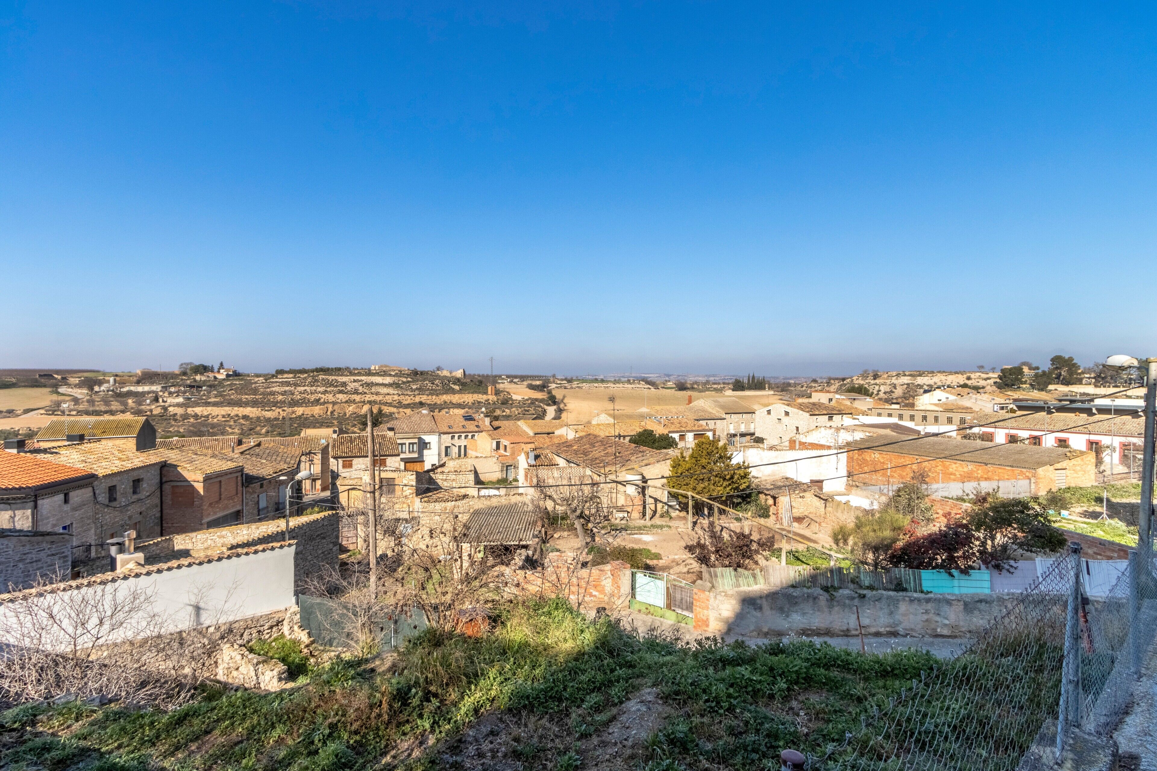 Eine Stadt mit Steinhäusern, blauem Himmel und Blick auf das Meer in der Ferne.