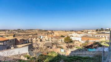 A town with stone buildings, a clear sky, and a distant view of the sea.