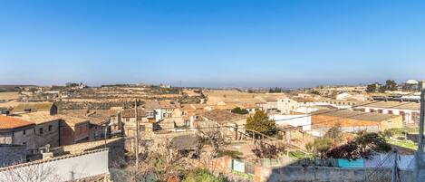 Eine Stadt mit Steinhäusern, blauem Himmel und Blick auf das Meer in der Ferne.