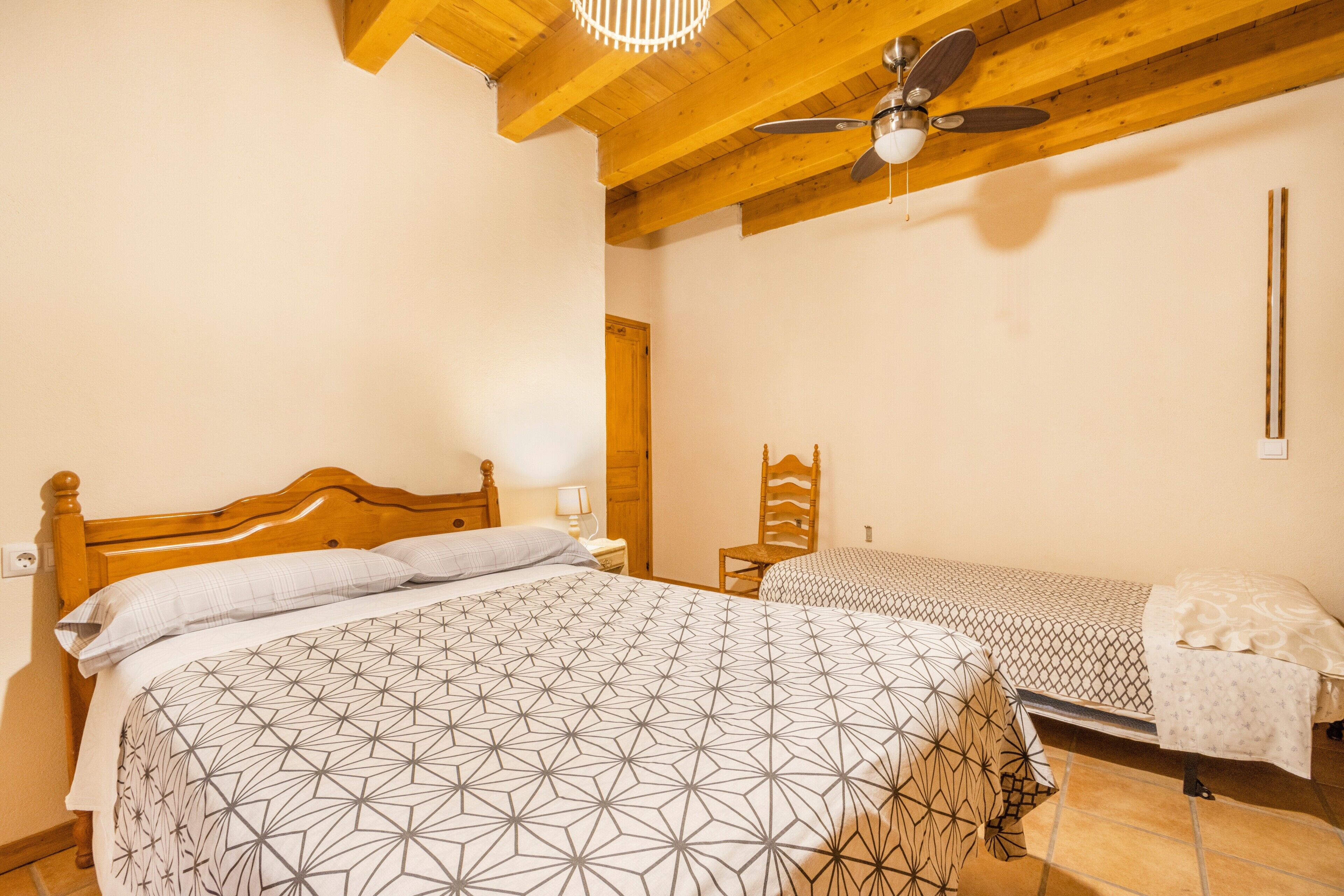 Un dormitorio con dos camas, cabeceros de madera, ventilador de techo y suelo de madera.