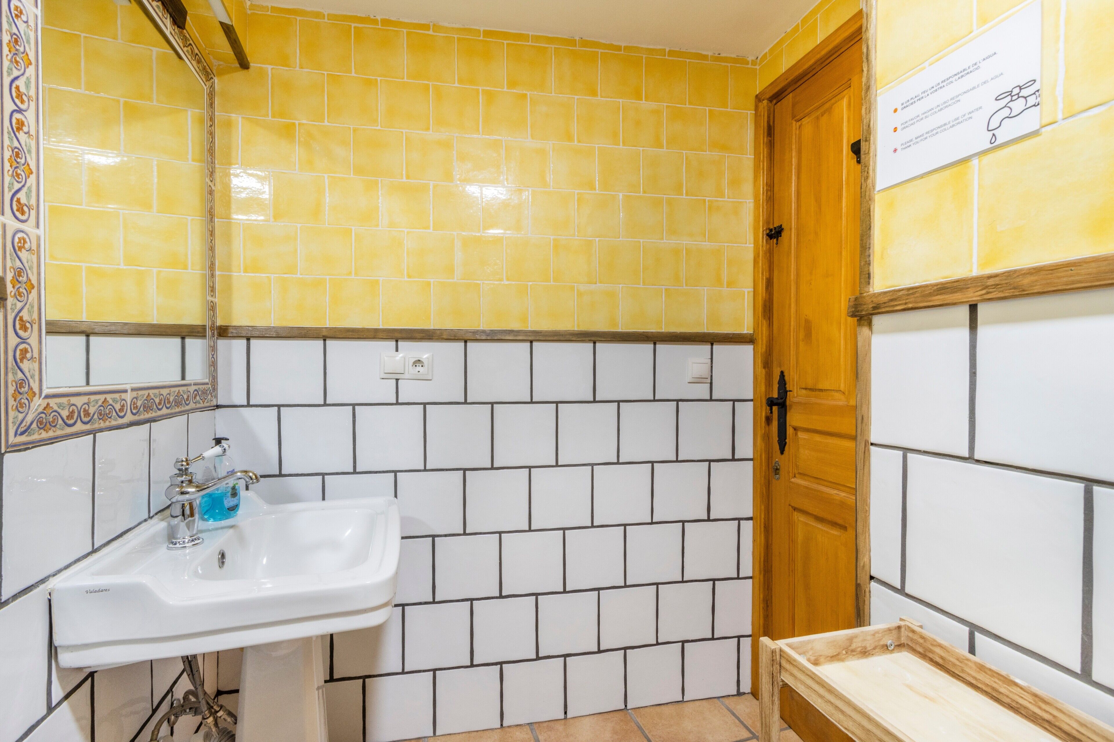Un bagno con lavandino, specchio e pareti piastrellate.
