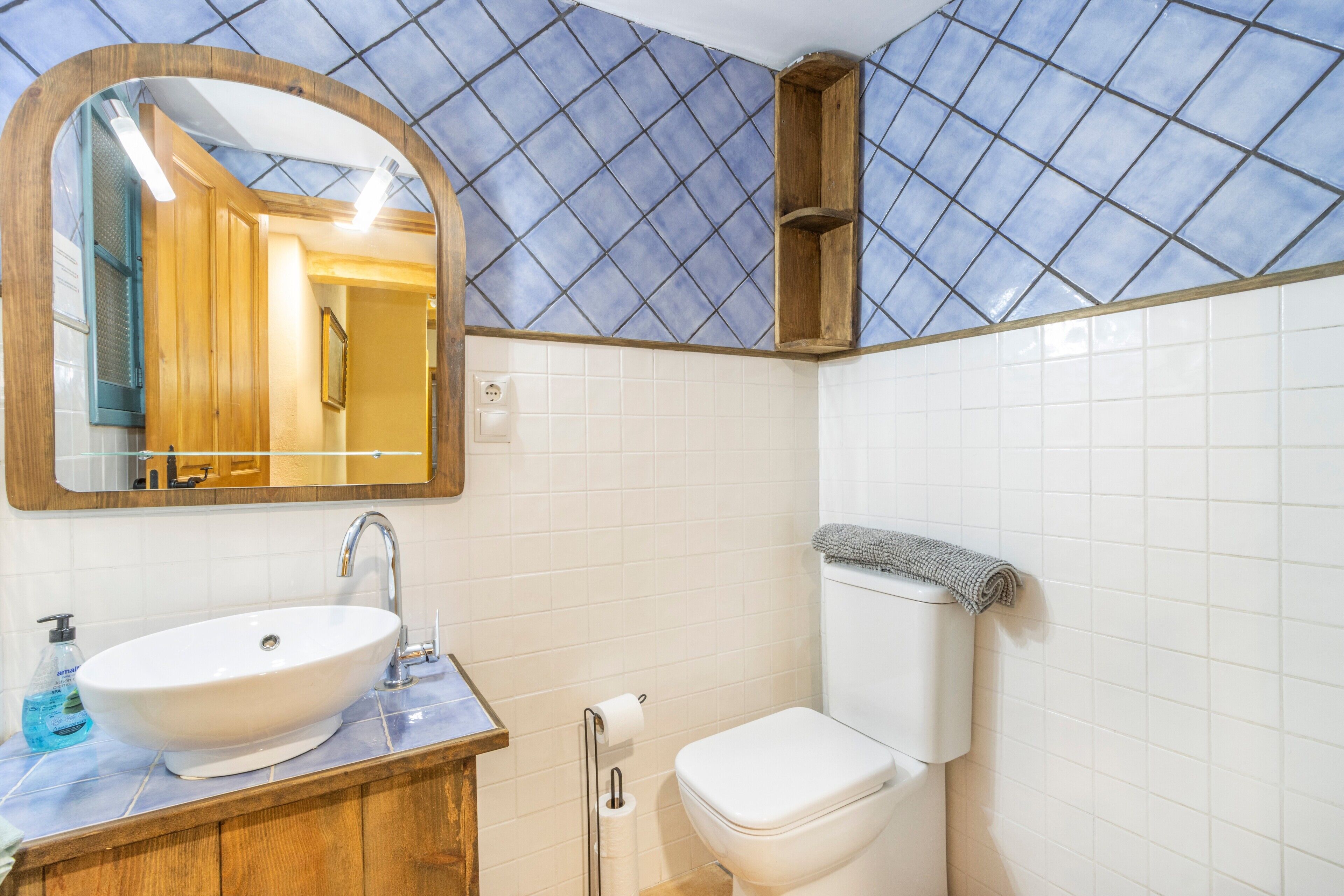 Un baño con lavamanos, espejo y retrete blanco.