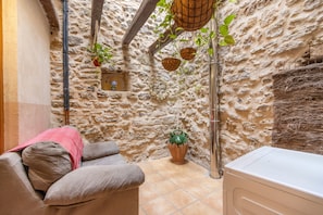 A stone-walled room with a sofa, a small potted plant, and a washing machine.
