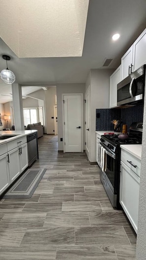 A modern kitchen with grey cabinets, a stainless steel oven, and a herringbone-patterned floor. - Stylish Escape/3BDRM & fireplace (El Paso)