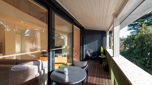 A modern outdoor balcony with a sofa, a round table, and a chair. - Porto Luxe Stay: Garden & Pool (Porto)