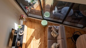 A modern living room with a wooden floor, a sofa with cushions, a coffee table, and a dining area with chairs and a table. - Porto Luxe Stay: Garden & Pool (Porto)