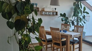 A dining area with wooden chairs and a table, surrounded by potted plants. - Cozy vacation apartment near Bamberg, dogs welcome! (Bischberg)