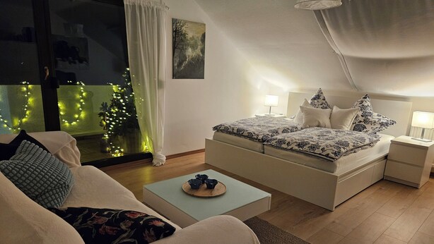 A bedroom with a bed, bedside tables, a sofa, and a coffee table. - Cozy vacation apartment near Bamberg, dogs welcome! (Bischberg)