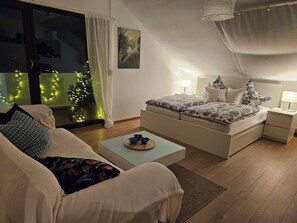 Un dormitorio con cama, mesitas de noche, un sofá y una mesa de centro.