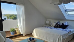 A cozy bedroom with a bed, a sofa, a small table, and a potted plant. - Cozy vacation apartment near Bamberg, dogs welcome! (Bischberg)