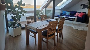 A modern living space with a dining area, a sofa, and a view of the outdoors. - Cozy vacation apartment near Bamberg, dogs welcome! (Bischberg)