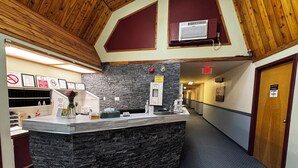 A reception area with a stone counter, wooden ceiling, and a red exit sign. - Zero-100 Motor Inn (Marathon)