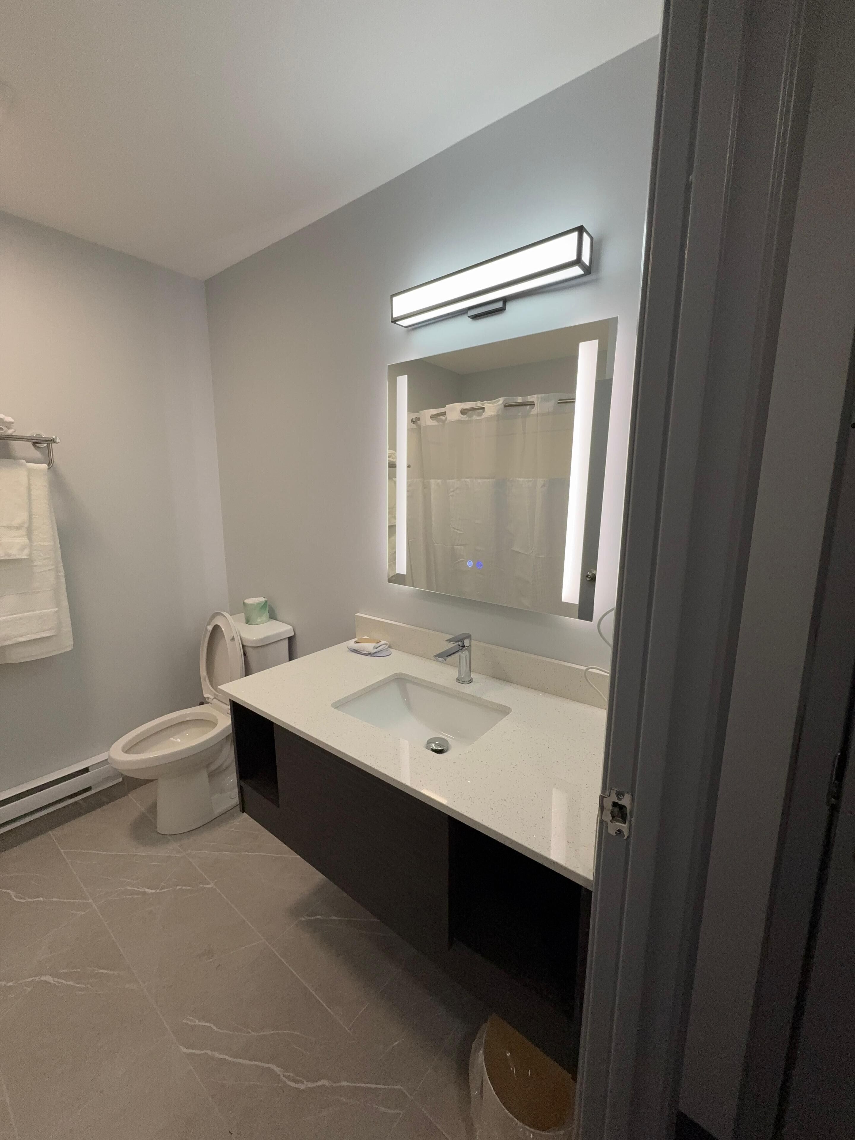 Un baño moderno con inodoro, lavabo y espejo.