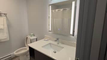 Un baño moderno con inodoro, lavabo y espejo.