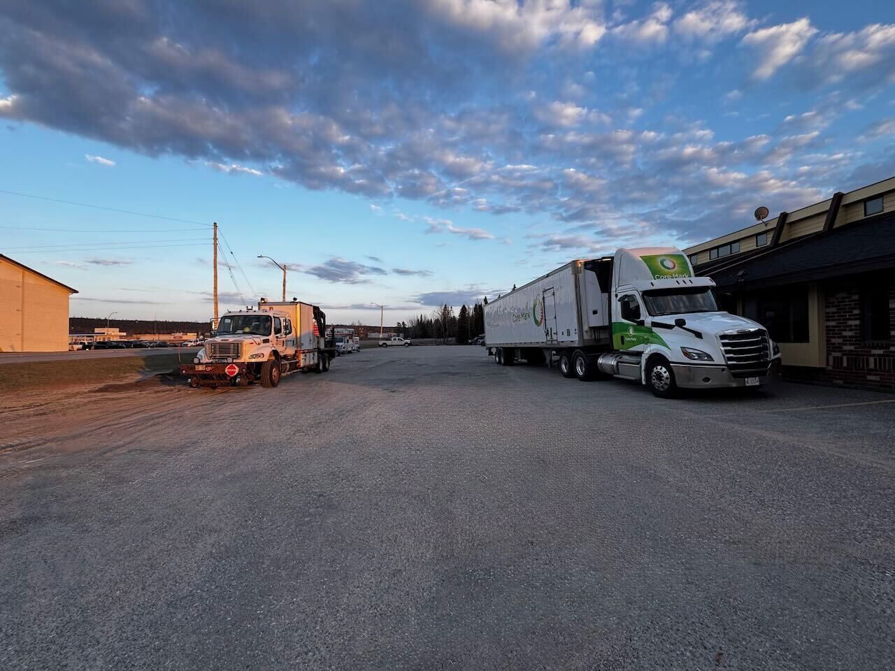 A parking lot with two trucks, one white and one orange, parked near a building with a sign that reads "CoreMark."