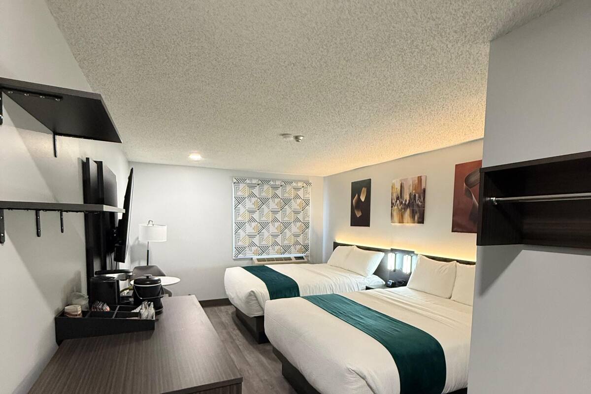 A hotel room with a bed, bedside table, and a desk with a chair.