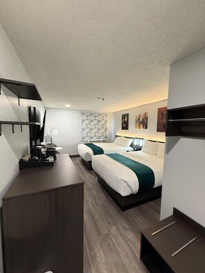A hotel room with a bed, bedside table, and a desk with a chair.