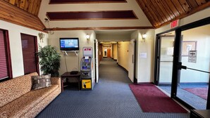 A hotel lobby with a reception desk, an ATM, a television, and a staircase leading to the restaurant. - Zero-100 Motor Inn (Marathon)