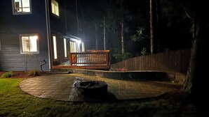 A house with a wooden deck, a fire pit, and a stone pathway.