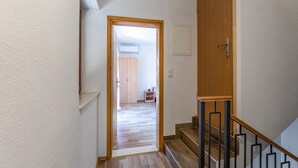 A hallway with a wooden door, a staircase with black railings, and a wooden floor. - 3 bedroom cozy home in Kremena (Kremena)