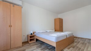 A modern bedroom with a wooden bed, a nightstand, a wardrobe, and a built-in bench. - 3 bedroom cozy home in Kremena (Kremena)