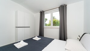 A hotel room with a bed, two white towels, a window with curtains, and a white wall. - 1 bedroom gorgeous apartment in Pridraga (Pridraga)