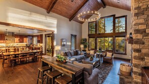 A spacious living area with a wooden dining table, sofas, and a stone fireplace. - Sunset Lodge: Luxury, Views & Endless Fun (Cle Elum)