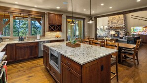 A spacious kitchen with a large island, wooden cabinets, and a stone fireplace. - Sunset Lodge: Luxury, Views & Endless Fun (Cle Elum)