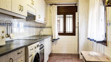 A compact kitchen with a washing machine, a sink, and a wooden bench.