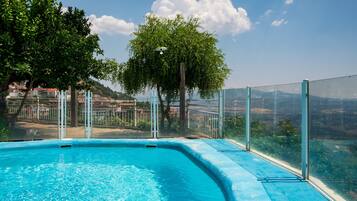 Ein Pool mit Glasbarriere, Bäumen und Blick auf Gebäude im Hintergrund.