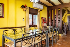A dining area with a glass table and chairs, a staircase with patterned tiles, and a yellow wall. - Country House 'El Rincón Del Duende' with Mountain View, Wi-Fi and Air Conditioning (Pedro Bernardo)