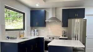 Una cucina moderna con mobili blu scuro, elettrodomestici in acciaio inossidabile e pavimento in legno.
