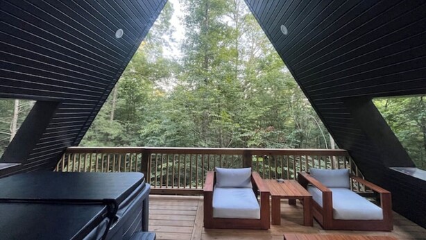 Una terrazza triangolare con mobili in legno e vista su una foresta.