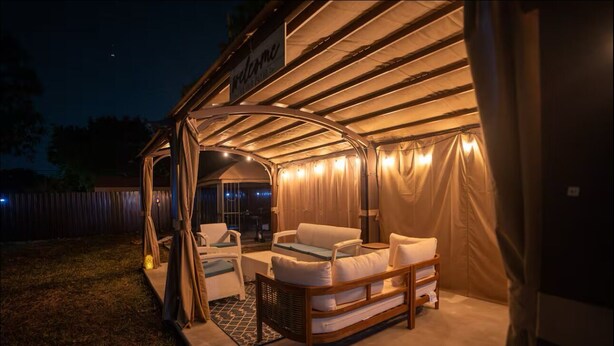 An outdoor covered seating area with a 'Welcome' sign, cushioned seating, and a small table. - Charming 3BR Miami Home with Stylish Lounge, Coffee Bar & Peaceful Vibes (Miami)