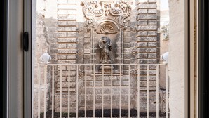 Un muro in pietra con una statua, un cancello in metallo e un telaio di finestra.