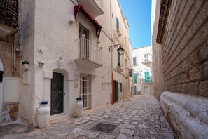 A narrow cobblestone street flanked by historic buildings with balconies, a clear blue sky, and a white door with a number plaque. - Studio 'Carolina 3' with Shared Terrace, Wi-Fi and Air Conditioning (Monopoli)