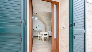 A room with a wooden door, a white table, and a white chair. - Apartment 'Casa Sardella, Nel Centro Storico' with Wi-Fi and Air Conditioning (Monopoli)
