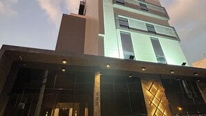 A modern building with a prominent vertical structure and a glass facade. - Melhores Flats - Excelente junto ao mar (João Pessoa)