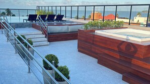 A rooftop terrace with lounge chairs, a hot tub, and a view of the ocean. - Melhores Flats - Excelente junto ao mar (João Pessoa)