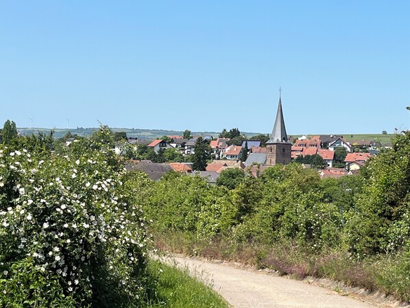 A rural village with a prominent church steeple, surrounded by houses and greenery. - "Kapellenberg" Studio in the Former Wine Cellar (Großkarlbach)